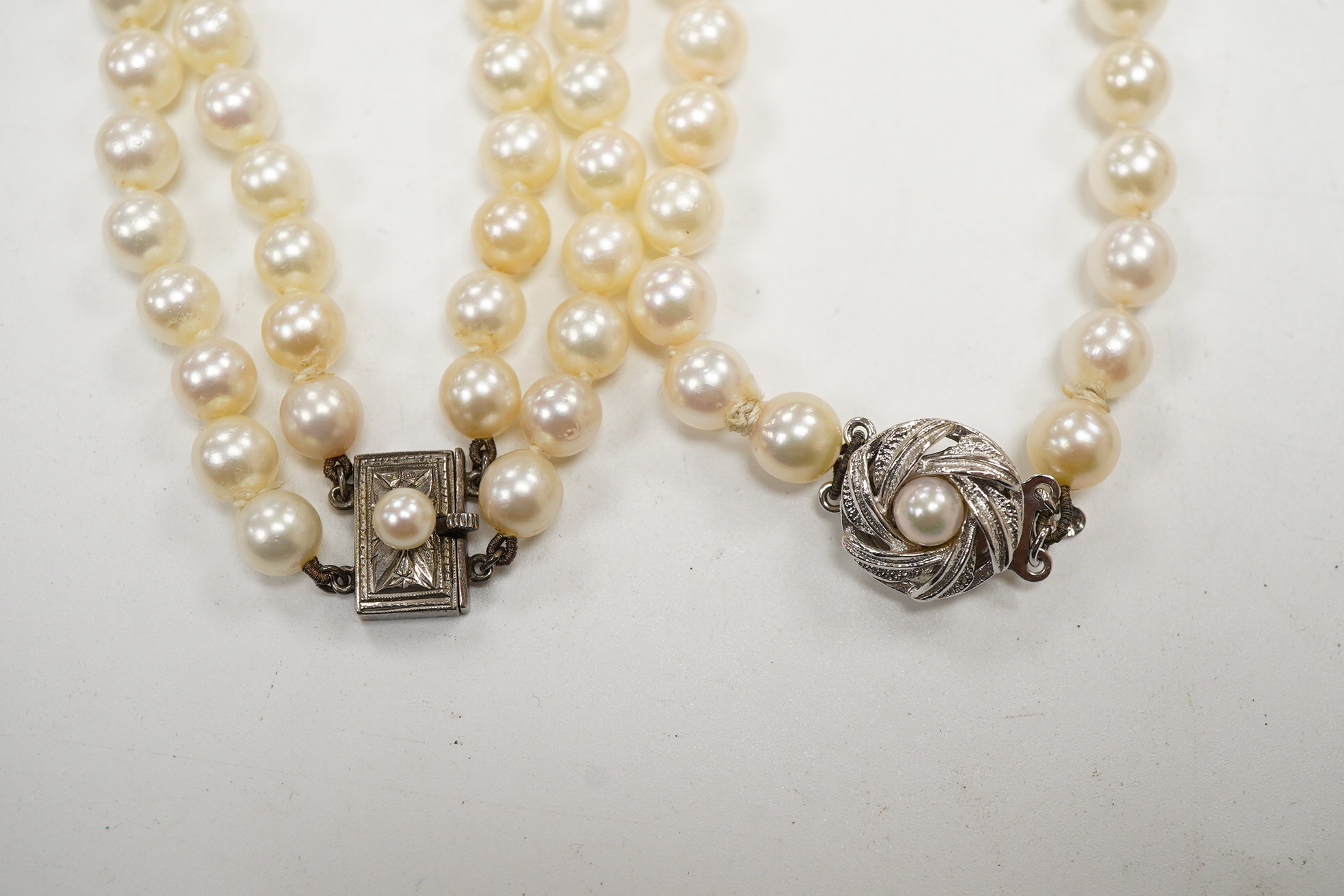 A Mikimoto double strand cultured pearl choker necklace, with cultured pearl set white metal clasp, 38cm, together with a single strand cultured pearl necklace, with cultured pearl set white metal clasp engraved 'silver'